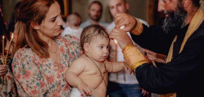 Intimate moment capturing a baby's baptism in a church with family present.