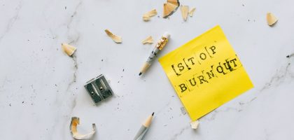 Pencil and shavings with 'Stop Burnout' note on marble surface convey stress relief concept.