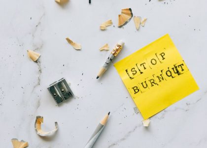 Pencil and shavings with 'Stop Burnout' note on marble surface convey stress relief concept.